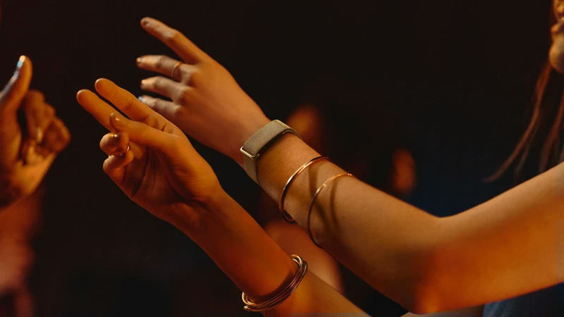 A close view of a person's outstretched arms, with a Fitbit tracker on one wrist.