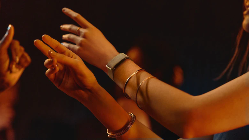 A close view of a person's outstretched arms, with a Fitbit tracker on one wrist.