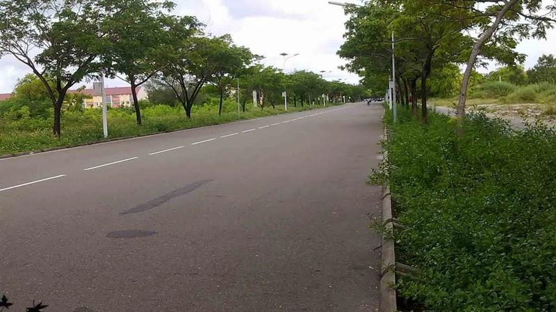 A road in Hulhumalé, Maldives, with buildings and vehicles along both sides.