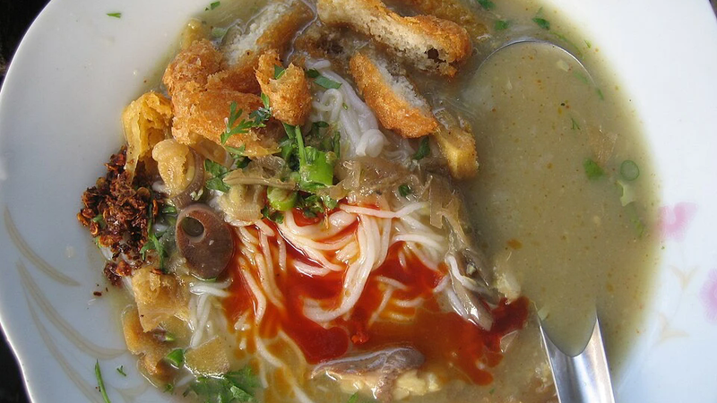 A bowl of noodles served with grilled fish.