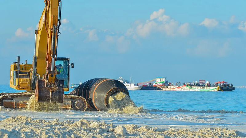 An excavator and dredge pipe pumping sand ashore at the Fushidhiggaru reclamation.