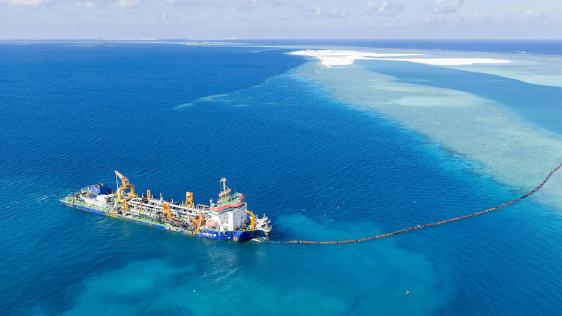 Aerial view of a dredger and pipeline in the turquoise lagoon at the Rasmalé reclamation site