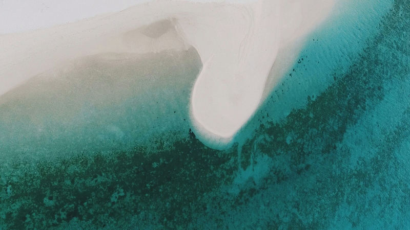 Aerial view of a white sandbank curving through a turquoise lagoon near Fenfushi