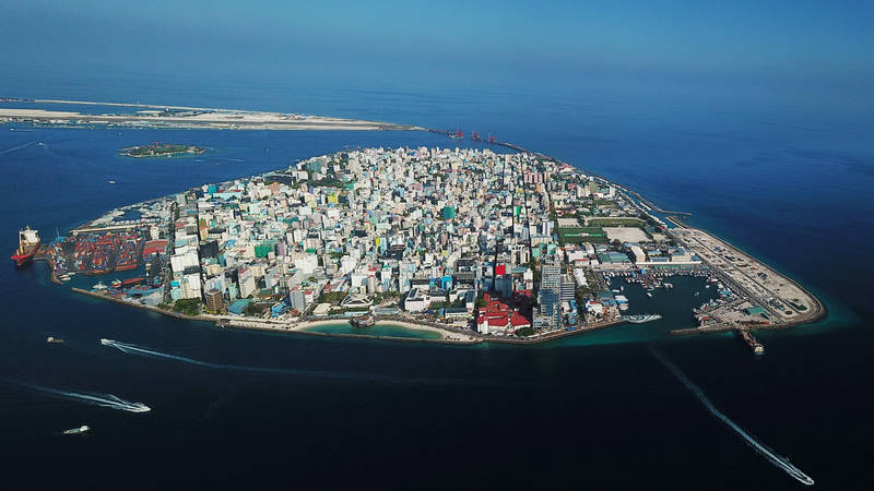 Aerial view of the densely built island of Malé with harbour areas and surrounding blue ocean