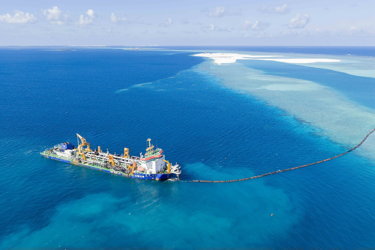 Aerial view of a dredger and pipeline in the turquoise lagoon at the Rasmalé reclamation site