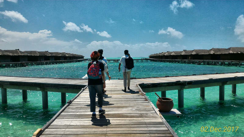Tourists walking along a jetty to water villas at a Maldives resort