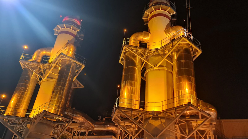 Tall exhaust stacks and steel framework at a STELCO power station, lit up at night