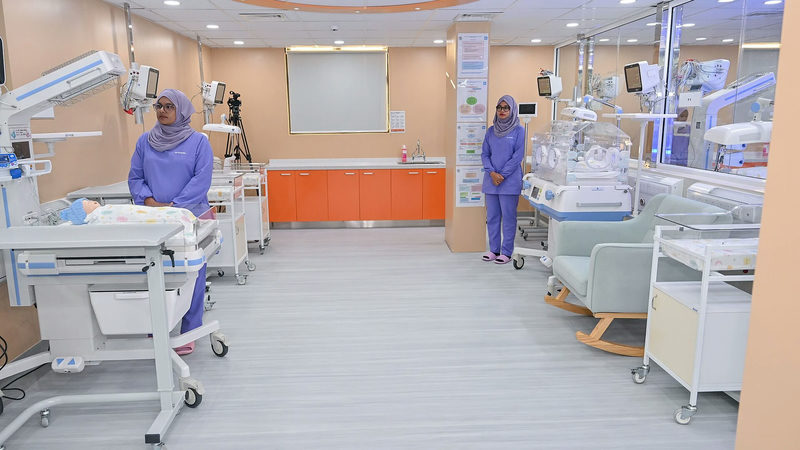 Two nurses in purple uniforms stand beside cots and incubators in a newborn care unit at Hulhumalé Hospital