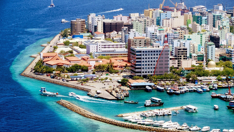 Aerial view of Malé's waterfront, with densely packed buildings and boats moored in the harbour