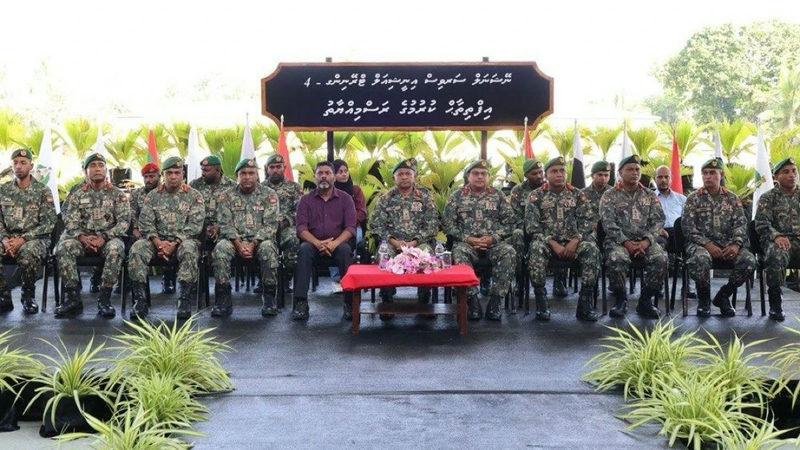 ވަޠަނީ ޚިދުމަތުގެ ތަމްރީނުގެ ރަސްމިއްޔާގެ ދިވެހި ސައިންބޯޑުގެ ދަށުގައި ސްޓޭޖުމަތީ އިށީނދެގެން ތިބި، ފެހި ބެރެޓާއި ސިފައިންގެ ޔުނިފޯމް އަޅައިގެން ތިބި އެމްއެންޑީއެފް އޮފިސަރުން