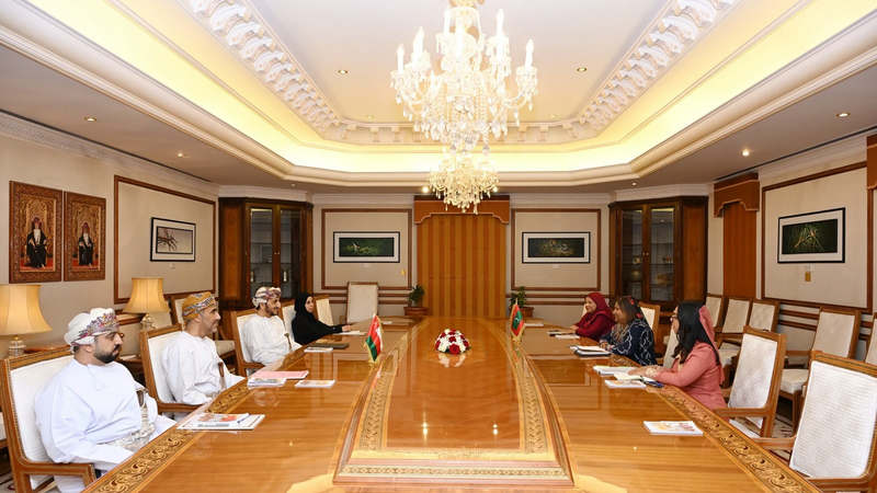 Maldivian and Omani officials seated facing each other at a long conference table with the two countries' flags, under a chandelier
