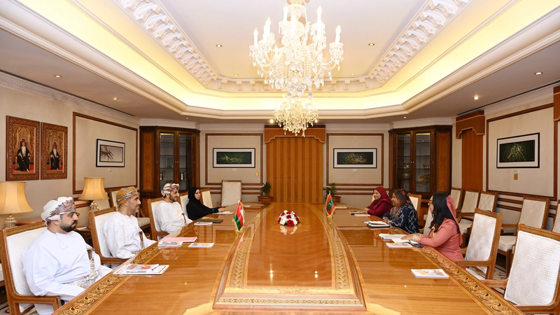 Maldivian and Omani officials seated facing each other at a long conference table with the two countries' flags, under a chandelier