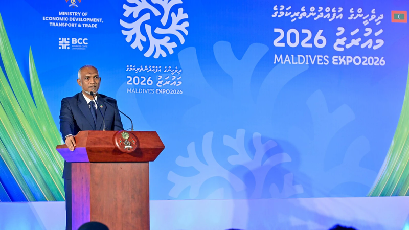 President Mohamed Muizzu speaking at a wooden podium in front of a blue Maldives Expo 2026 backdrop