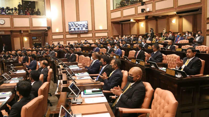 Members of parliament seated at their desks in the wood-panelled People's Majlis chamber, with public galleries above