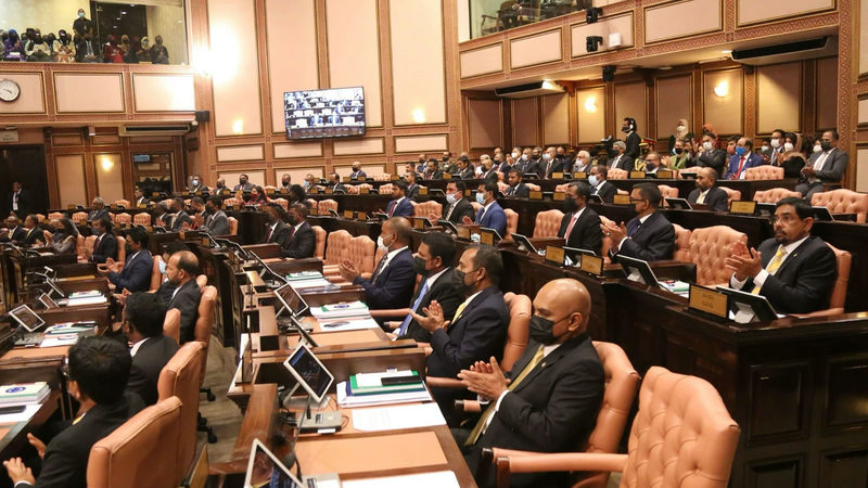 ރައްޔިތުންގެ މަޖިލީހުގެ ތަޅުމުގައި މޭޒުތަކުގައި އިށީނދެވަޑައިގެން ތިއްބަވާ މެންބަރުން، މަތީގައި ގެލަރީތައް