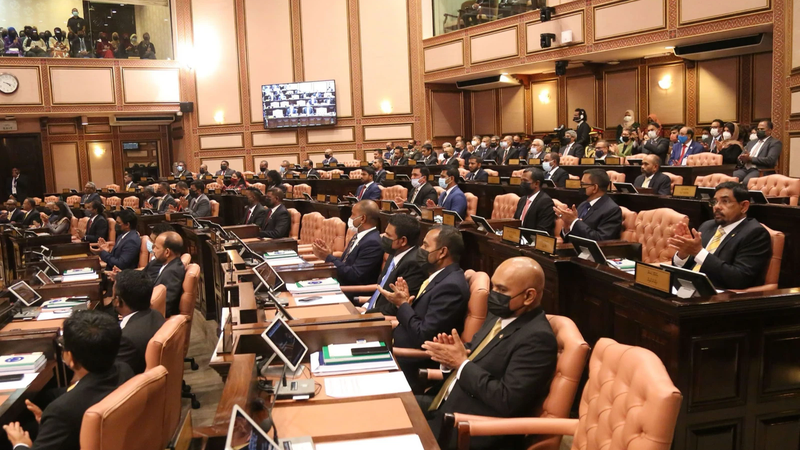 Members of parliament seated at their desks in the wood-panelled People's Majlis chamber, with public galleries above