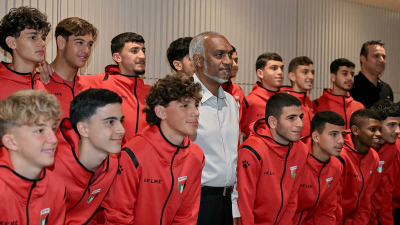 President Mohamed Muizzu stands among young Palestinian footballers in red team tracksuits.