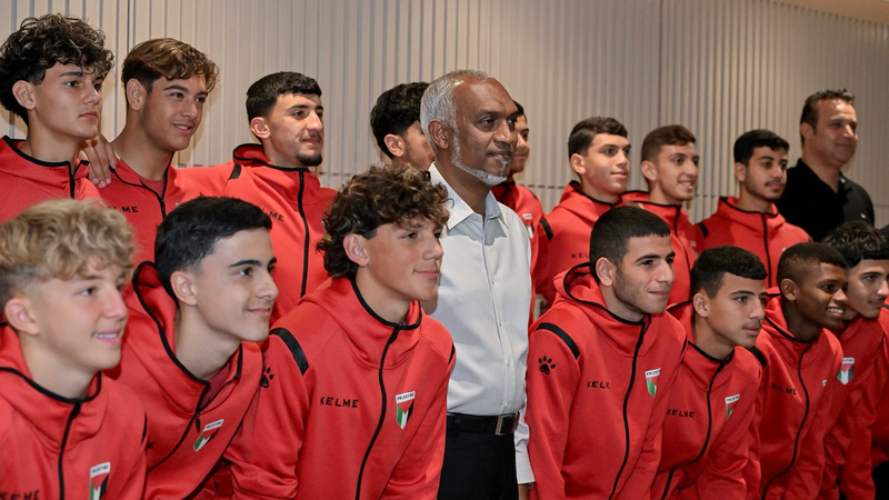 President Mohamed Muizzu stands among young Palestinian footballers in red team tracksuits.