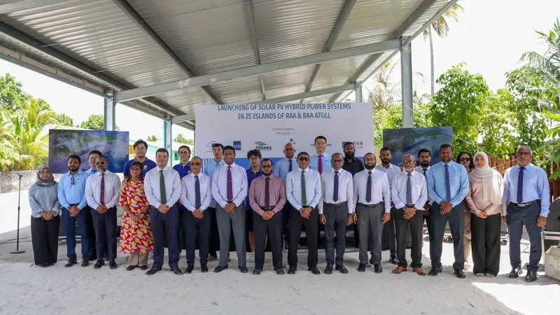 A group of officials in shirts and ties stand in a row under a metal canopy in front of a banner about launching solar PV hybrid power systems in Raa and Baa atolls