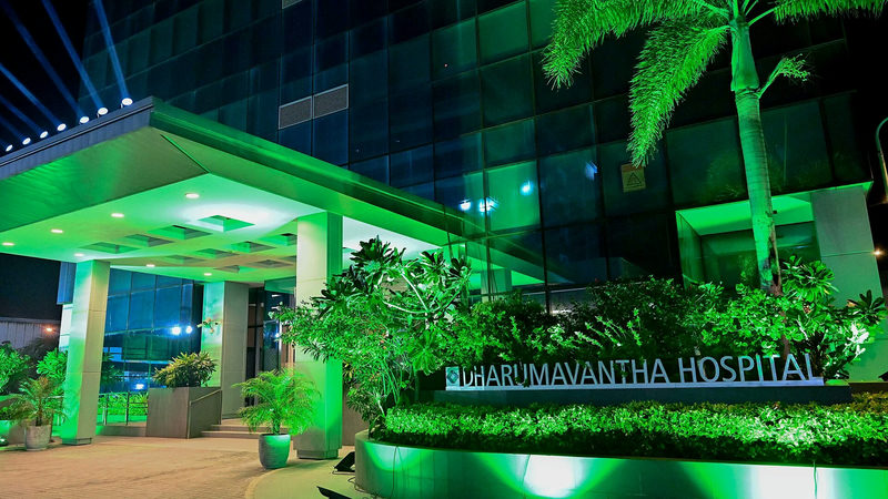 Entrance of Dharumavantha Hospital, a government tertiary hospital in the Maldives, lit green at night with its name sign