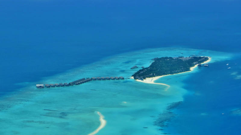 Aerial view of Landaa Giraavaru island in Baa Atoll with a long row of overwater villas over a turquoise lagoon